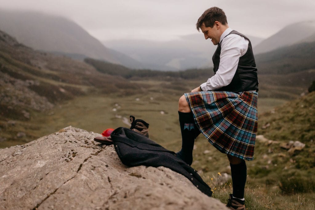 Groom getting changed in the landscape on his Scottish elopement in Corrie Fee, Cairngorms National Park