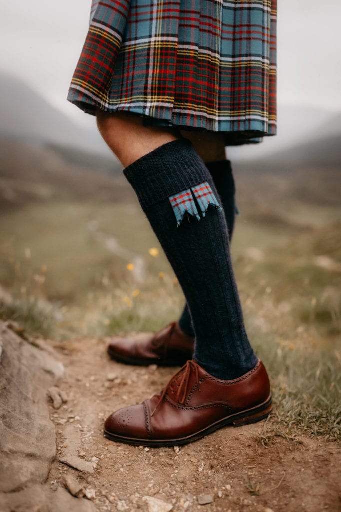 The tartan flashes of the groom's family tartan as he prepares for elopement ceremony in the Scottish Cairngorms 