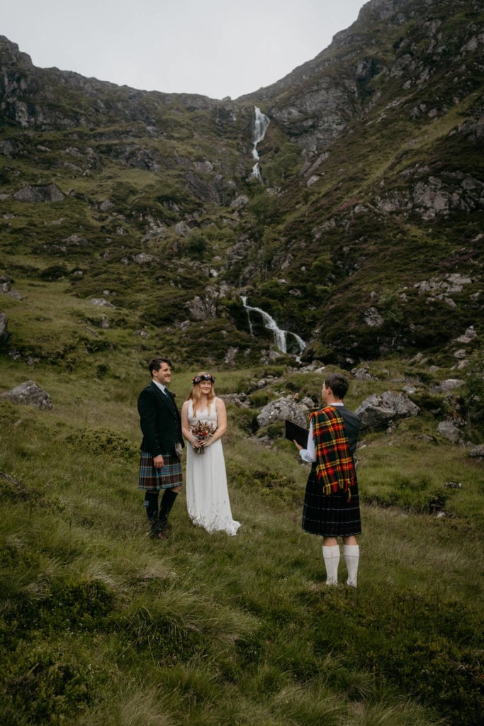Eloping couple during their ceremony in front of a waterfall at Corrie Fee, Cairngorms