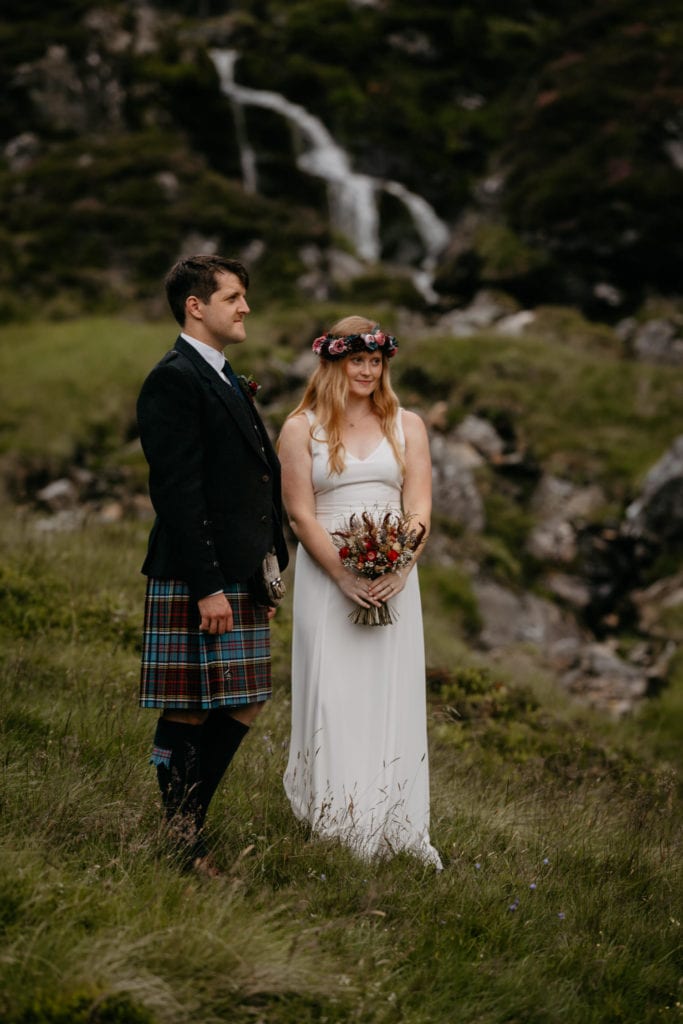 Eloping couple during their ceremony in front of a waterfall at Corrie Fee, Cairngorms