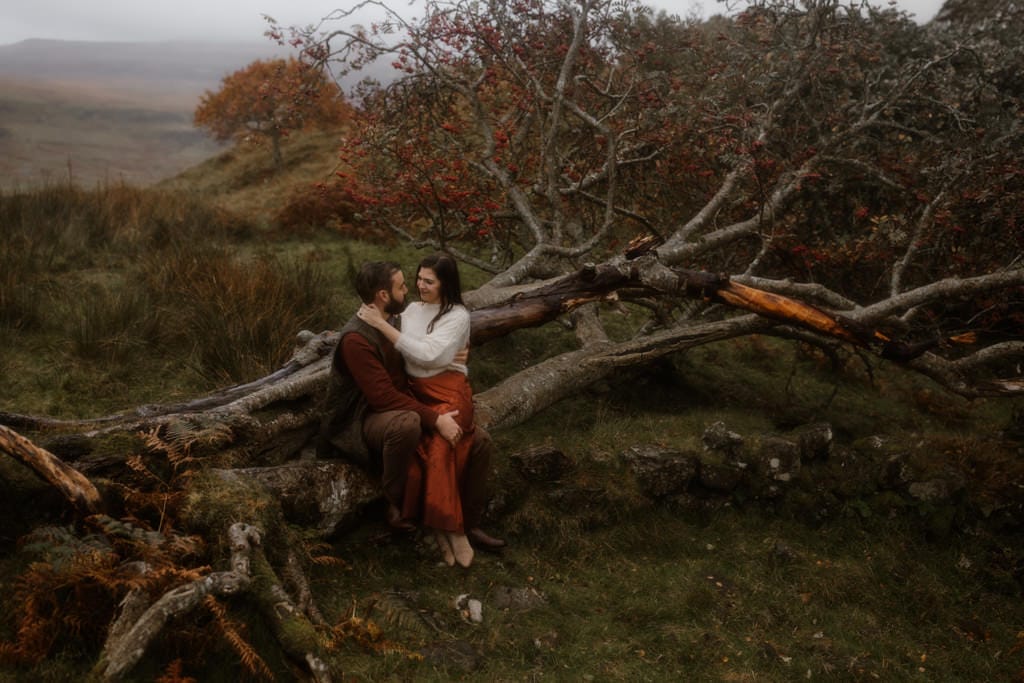 Couple sitting on tree during couple session, Fairy Glen Isle of Skye 
