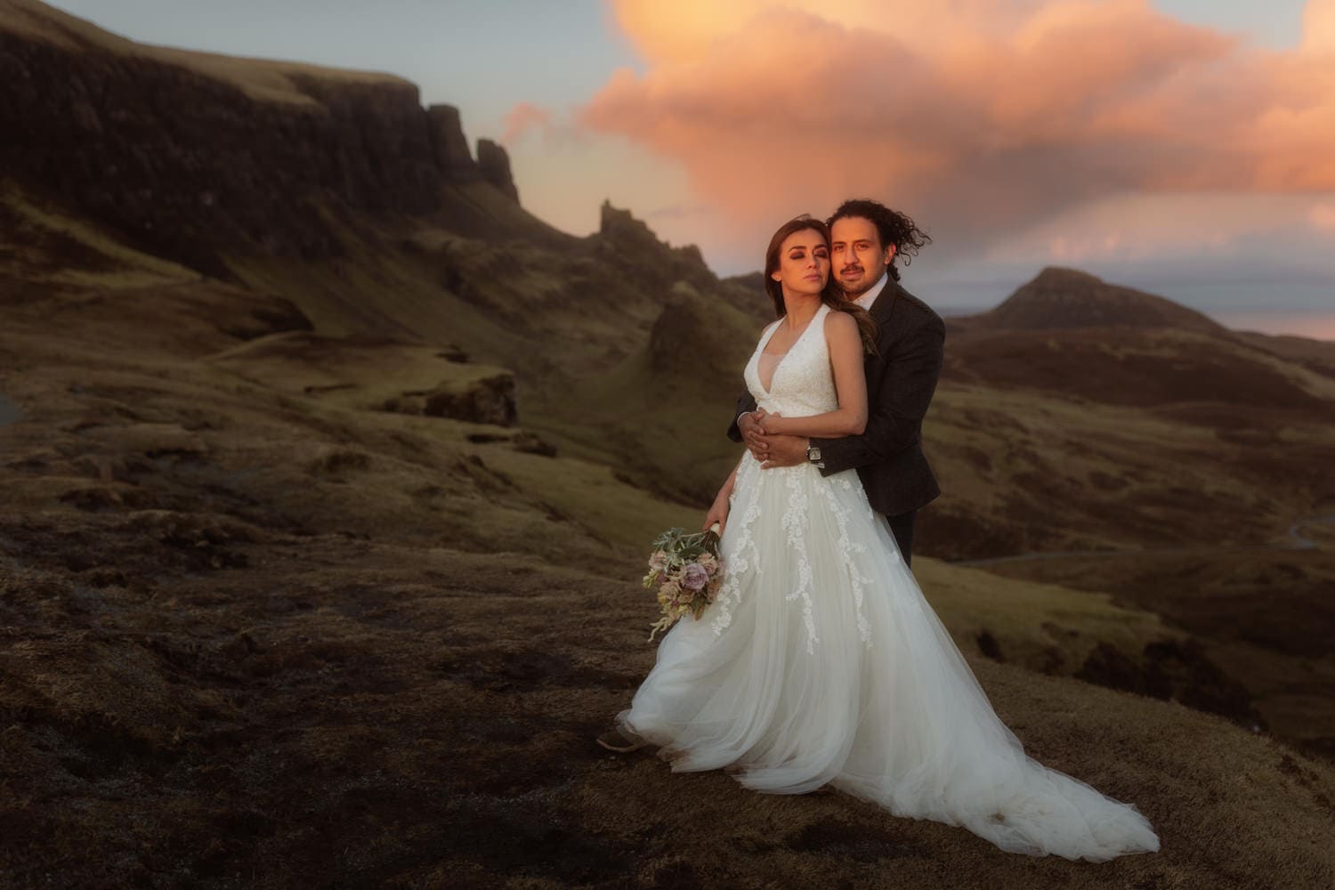 Eloping couple from Mexico embrace watching sunset at the Quiraing on the Isle of Skye.