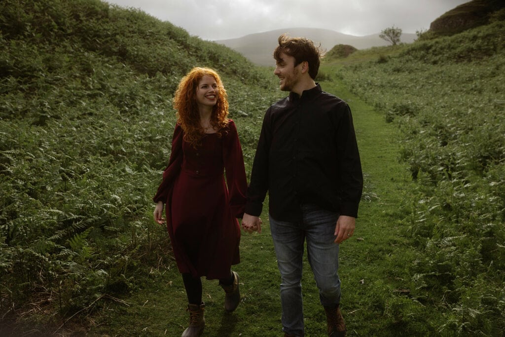 Ashley and Bobby walking hand in hand through the lush, rolling hills of the Isle of Skye, enjoying the breathtaking scenery together
